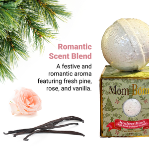 Mistletoe Kisses Bath Bomb by Mom Bomb – bath bomb resting on green gift box with pine, rose, and vanilla fragrance ingredients shown beside romantic scent callout