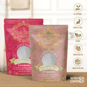 Two Mom Bomb bath salt bags—Pink Himalayan and Eucalyptus Rose—standing on a wooden counter with natural ingredient and certification icons on the right.